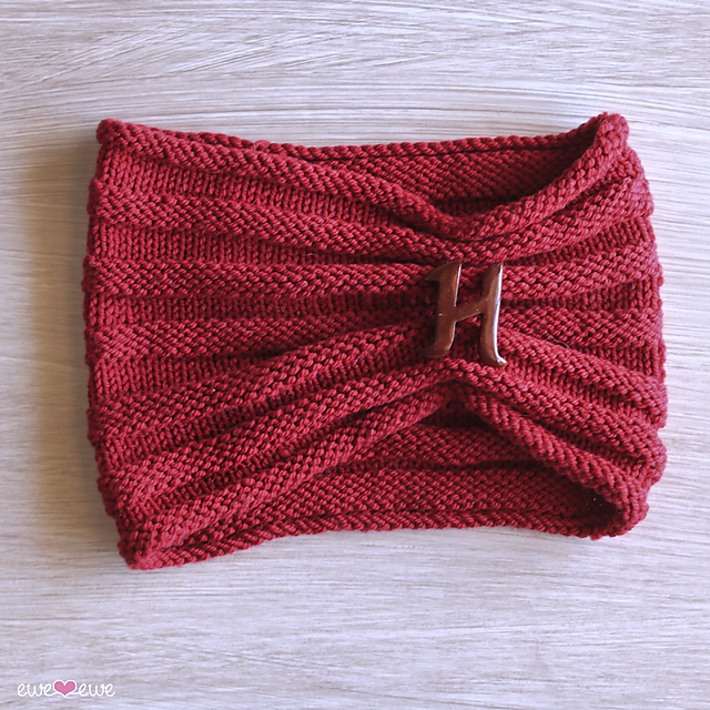 image of red knit cowl with knit and purl stitches on a neutral color woodgrain background.