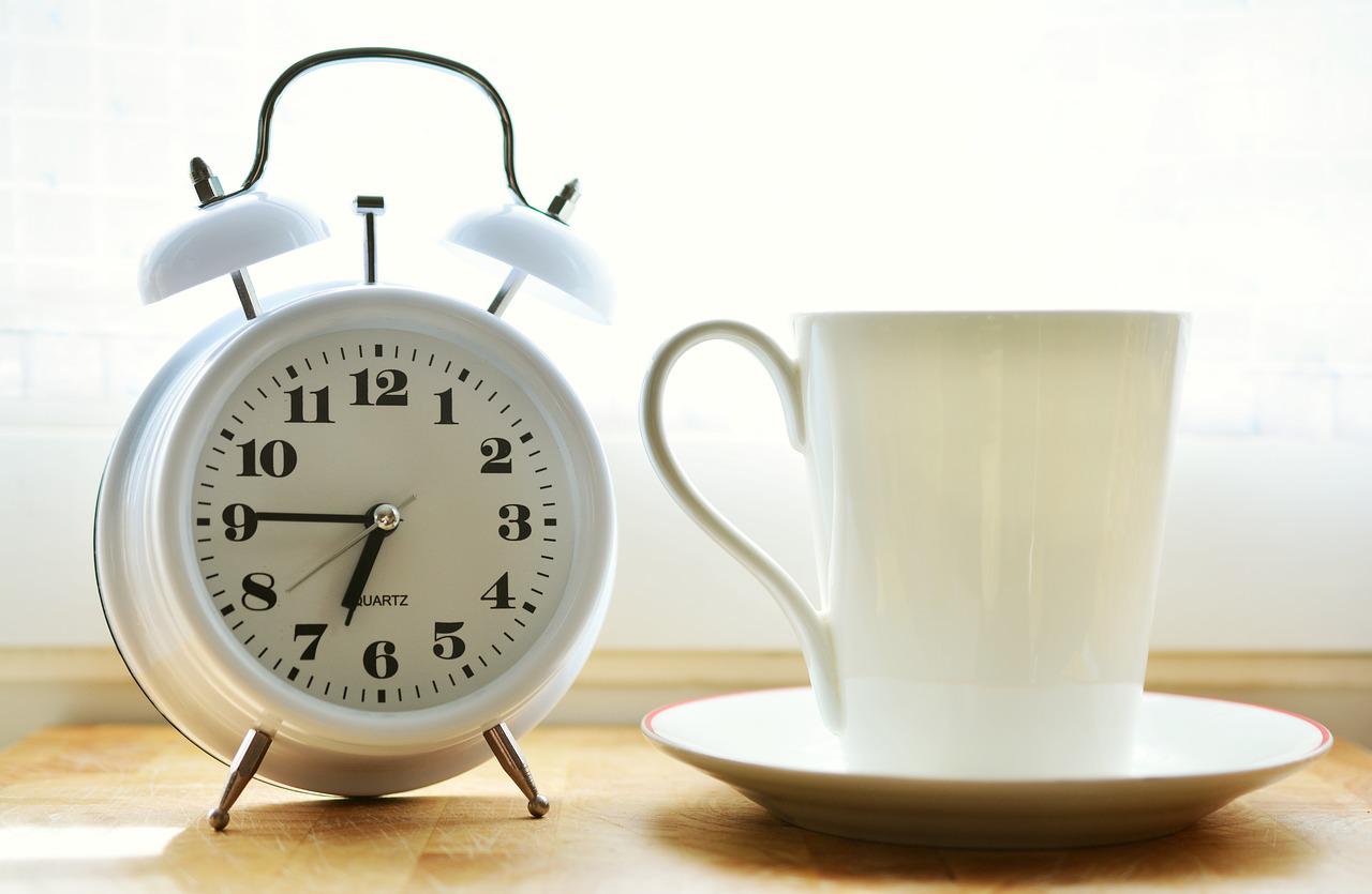picture of an alarm clock with a white background and a coffee mug on a table