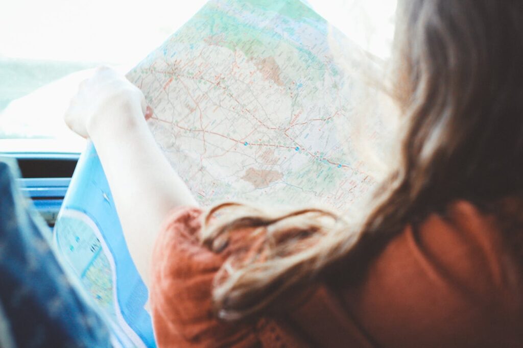 Side view of a woman looking at a map and sitting in a car